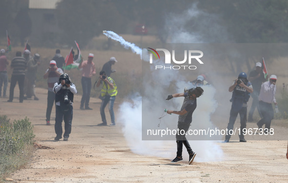 A Palestinian protestor throws back a tear gas canister towards member of the Israeli soldiers during clashes at a protest in support of Pal...