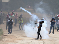 A Palestinian protestor throws back a tear gas canister towards member of the Israeli soldiers during clashes at a protest in support of Pal...