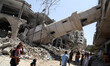 Palestinians walk past the collapsed minaret of a destroyed mosque in Gaza City, on July 3...