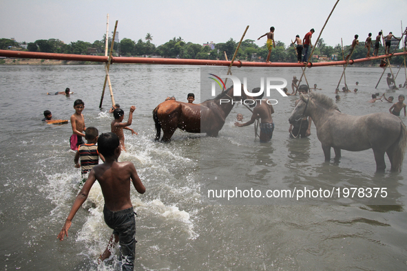 A man is bathing horses on the Buriganga River during the hot weather in Dhaka, Bangladesh, on May 24, 2017.  