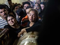 Relatives of Coptic Christians who were killed during a bus attack, surround their coffins, during their funeral service, at Ava Samuel dese...