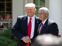 President Donald Trump greets VP Mike Pence before making his statement that the United States is withdrawing from the Paris Climate Accord,...