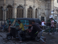 Two young egyptians are pushing a Tuk Tuk to make it start in Old Cairo on June 15, 2017 (