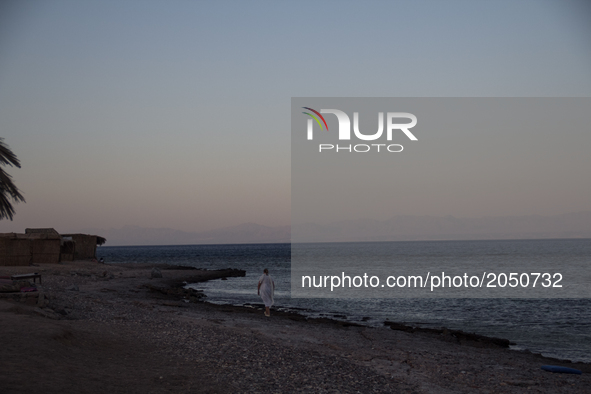 A woman walks on the shore of Aqaba's gulf in a Beduin camp near Nuweibaa on June 5, 2017 