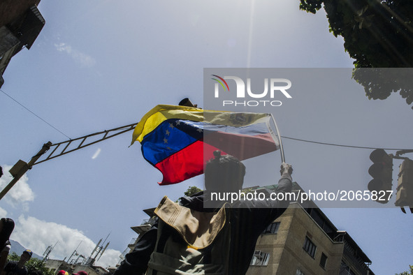 A demonstrator holds a venezuelan flag during a street blocking. Demonstrators use mask to cover their faces from the security forces. Carac...