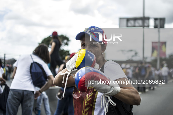 A woman poses with a pair of boxing gloves during a demonstration. Demonstrators use mask to cover their faces from the security forces. Car...