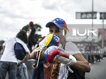 A woman poses with a pair of boxing gloves during a demonstration. Demonstrators use mask to cover their faces from the security forces. Car...