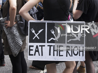 A protester holding a banner reading 'eat the rich' attends a protest march against the G20 Summit with the topic 'Solidarity without border...