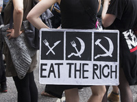 A protester holding a banner reading 'eat the rich' attends a protest march against the G20 Summit with the topic 'Solidarity without border...