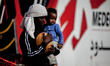 A migrant woman carries a child as they disembark from the Italian rescue ship Vos Prudenc...