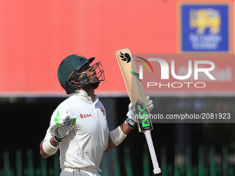 Zimbabwe's Sikandar Raza looks up to the sky and reacts after scoring fifty runs during the third day's play of the only test cricket match...