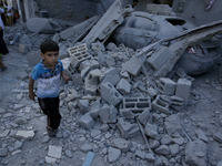 Palestinian boy walking after a nearby house was hit by an Israeli military strike in Rafah in the southern Gaza Strip on August 10, 2014. I...