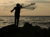  A Palestinian fisherman throws his net at a beach near the port of Gaza (