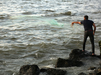  A Palestinian fisherman throws his net at a beach near the port of Gaza (