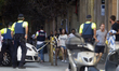 People are escorted by Spanish policemen outside a cordoned off area after a van ploughed...