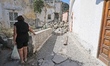 A woman walks near an house destroyed in the earthquake in one of the more heavily damaged...