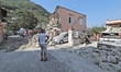 A man walks near an house destroyed in the earthquake in one of the more heavily damaged a...