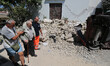 People walk near a house, destroyed in the earthquake in one of the more heavily damaged a...