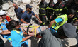 Italian emergency workers evacuate on a stretcher a boy who was was trapped by rubble, in...