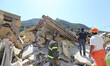 Rescuers team walk near a house, destroyed in the earthquake in one of the more heavily da...