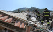 Rescuers team walk near a house, destroyed in the earthquake in one of the more heavily da...