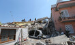 Rescuers team walk near a house, destroyed in the earthquake in one of the more heavily da...
