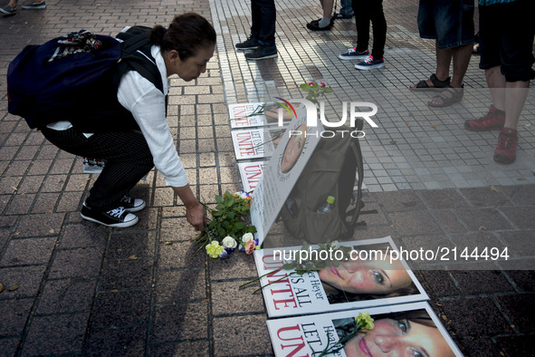 A woman poses a flower on the photo of Heather Heyer during the standing silent appeal, a hundred people gathered in shibuya against racism...