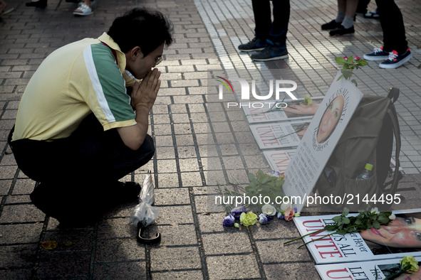 A man prays on the photo of Heather Heyer during the standing silent appeal, a hundred people gathered in shibuya against racism and violenc...