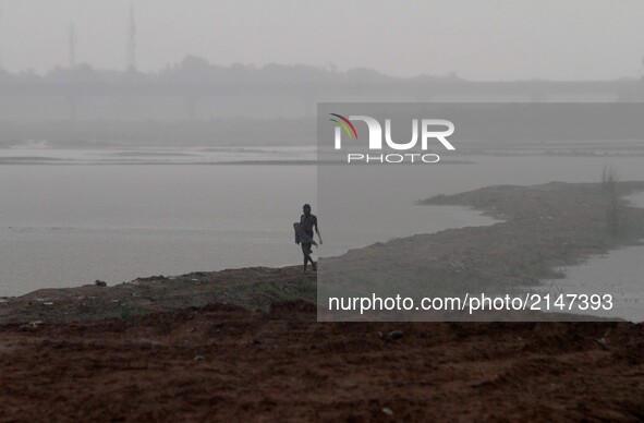 A villager walks back home wade throw in the rain after complete his bath in the water of river Kuakhai outskirts of the eastern Indian stat...