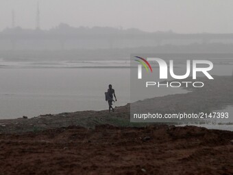 A villager walks back home wade throw in the rain after complete his bath in the water of river Kuakhai outskirts of the eastern Indian stat...