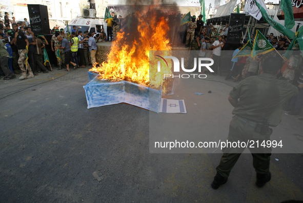 RAFAH, GAZA STRIP, PALESTINE - AUGUST 17:  Masked Hamas members burn a cut-out of a Star of David during a demonstration in support of the H...