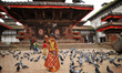 A Nepalese young girl impersonate as a Kumari or living Goddess offering grains towards pi...