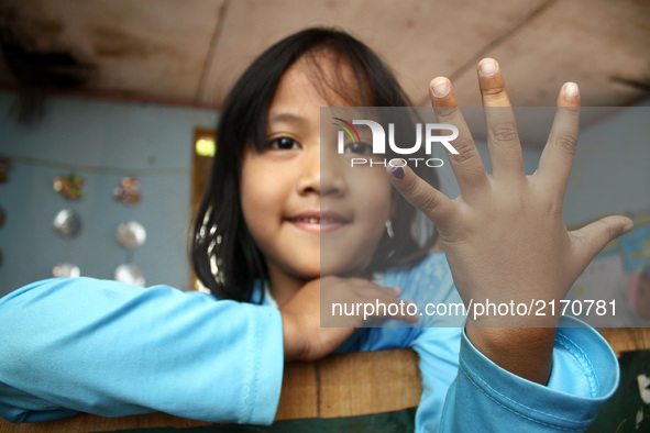 A girl shows her blue little finger, a sign that she has got Measles and Rubella vaccine at an integrated health service posts in Wanasari V...