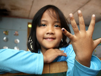 A girl shows her blue little finger, a sign that she has got Measles and Rubella vaccine at an integrated health service posts in Wanasari V...