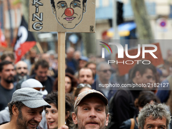 A protester holds a placard with a caricature of French President Emmanuel Macron. More than 10000 protesters took to the streets of Toulous...