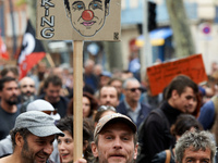 A protester holds a placard with a caricature of French President Emmanuel Macron. More than 10000 protesters took to the streets of Toulous...