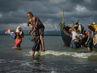Rohingya Muslim refugees disembark from a boat on the Bangladeshi side of Naf river in Teknaf on September 13, 2017. International divisions...