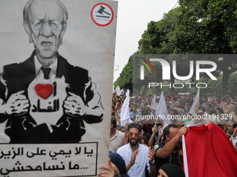 Protesters raise a portrait of Tunisian president Beji Caid Essebsi that reads ' I Love corruption' during a march held under the slogan ‘fi...