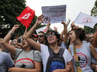 Protesters wave Tunisian flag and raise placards that read in Arabic 'firmness against the mafia regime' during a march held under the sloga...
