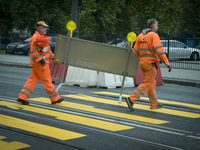Road workers are seen removing road signs near a makeshift pedestrian crossing on World Car-Free Day on September 22, 2017. (
