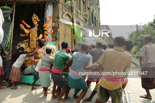 Indian Daily base labourers carry a statue of the Hindu goddess Durga from a workshop in Kumartoli, the idol makers' village, to a truck to...
