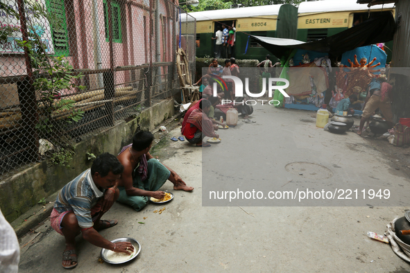 Indian labourers have their lunch prior to carrying a finished clay statue of the Hindu goddess Durga from a workshop in Kumartoli, the idol...