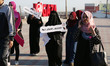 Palestinian women march on a street demonstration and carrying signs reading in Arabic ''U...