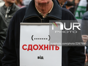 A man holds the plakard which says "die from your immunity" during the rally in front of Parliament. Mikheil Saakashvili gathers few thousan...