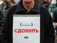 A man holds the plakard which says "die from your immunity" during the rally in front of Parliament. Mikheil Saakashvili gathers few thousan...