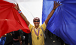 An anti-Government protester celebrating beneath a giant Thai flag after hearing that Thai...