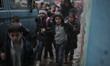 Palestinian school children walk in a flooded street during heavy rain in Gaza City on Nov...