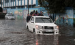 Palestinian school children walk in a flooded street during heavy rain in Gaza City on Nov...