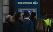 People await in front of the Bank of Ireland cash mashine, on a busy Friday, just a few da...