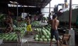 Workers lob watermelons to be arranged into a pyramid at a market in suburban Quezon City,...